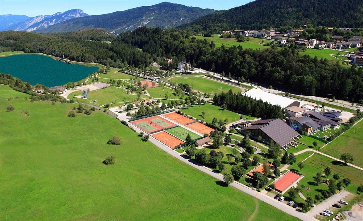 Vista aerea panoramica dell’Andalo Life Park con lago, campi sportivi e aree verdi